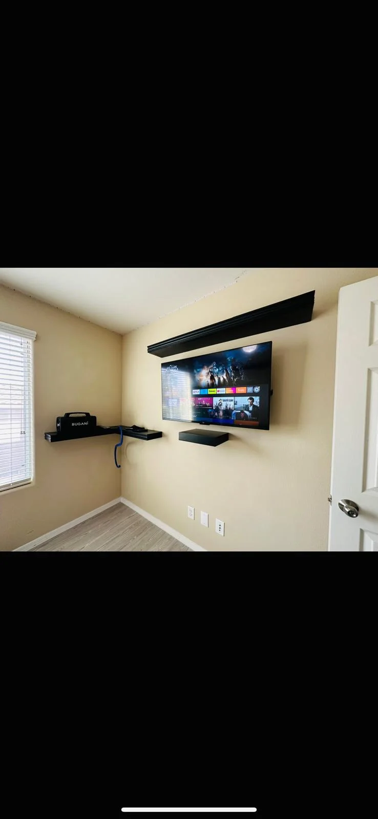 Wall-mounted TV with floating shelves in a bedroom