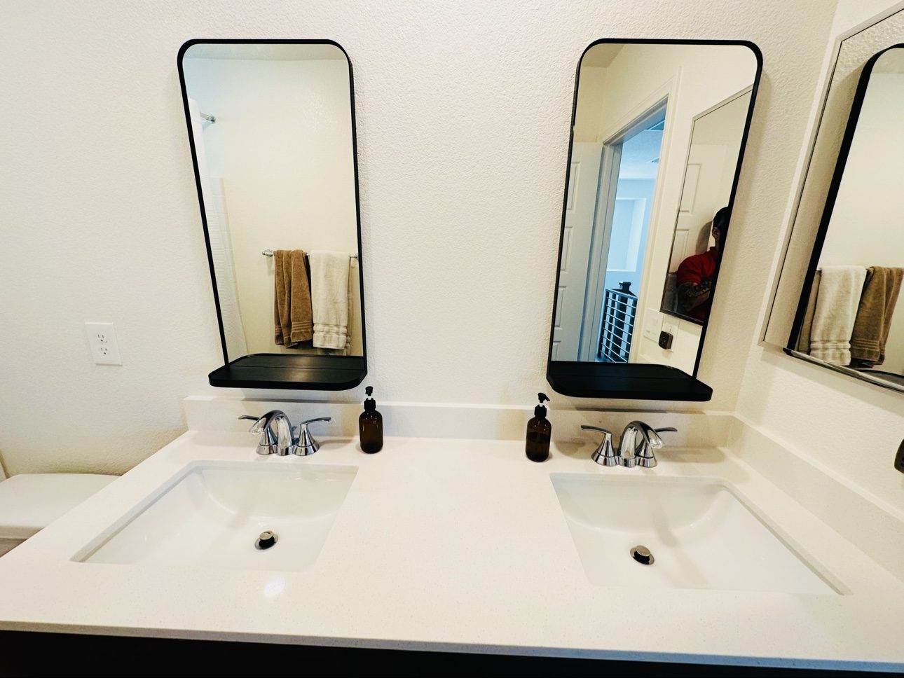 Two arched mirrors with shelf ledges hung over a double sink
