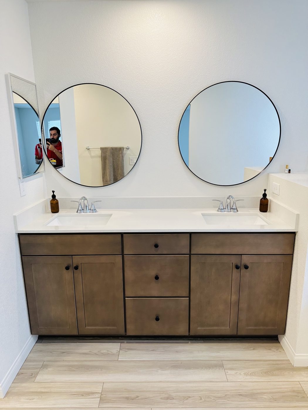 Two round black-framed mirrors hung level above a double-sink vanity